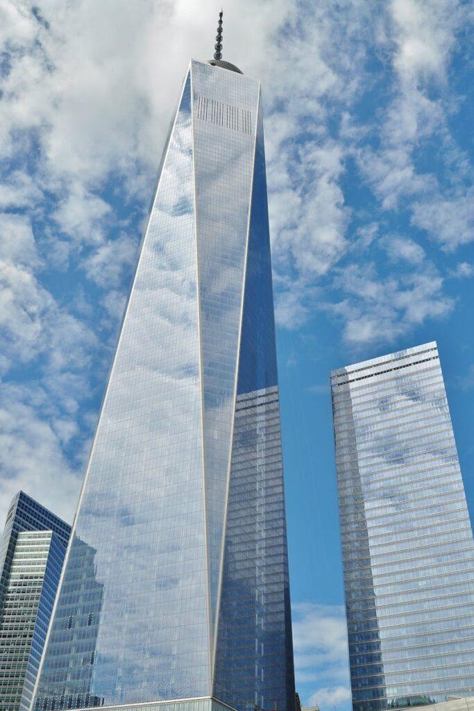 A striking view of One World Trade Center reflecting clouds in New York City.