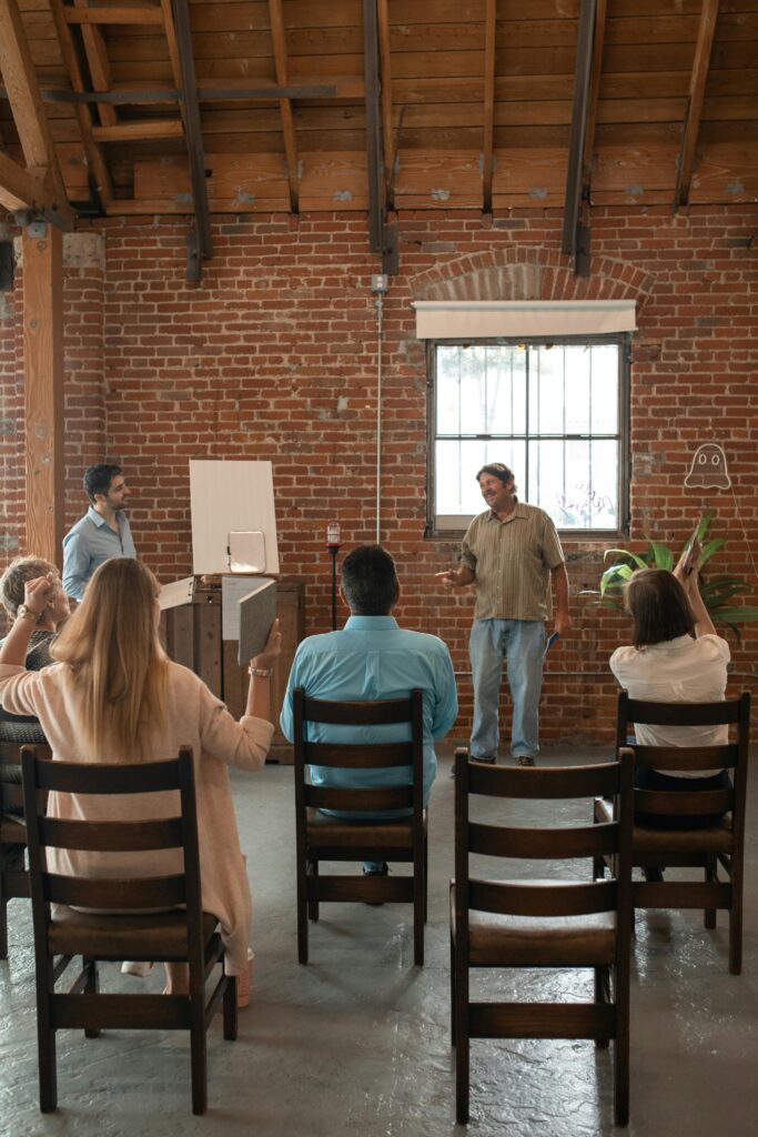 Adults attending a class in a rustic brick-walled room with a wooden ceiling.