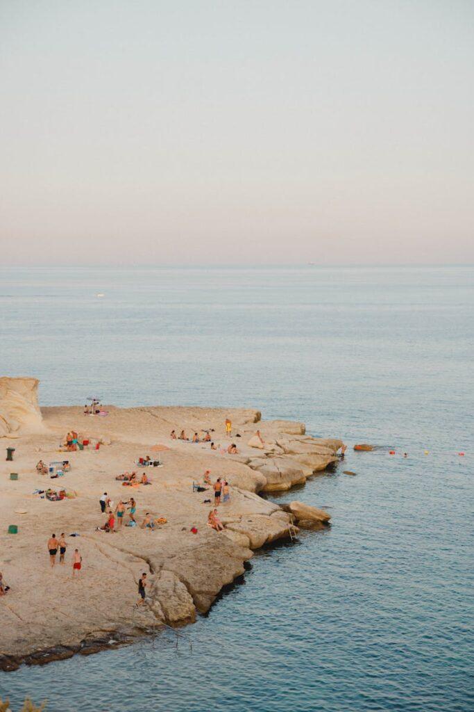Relax by the rocky shores of Mgarr, Malta, enjoying a tranquil summer day at the beach.