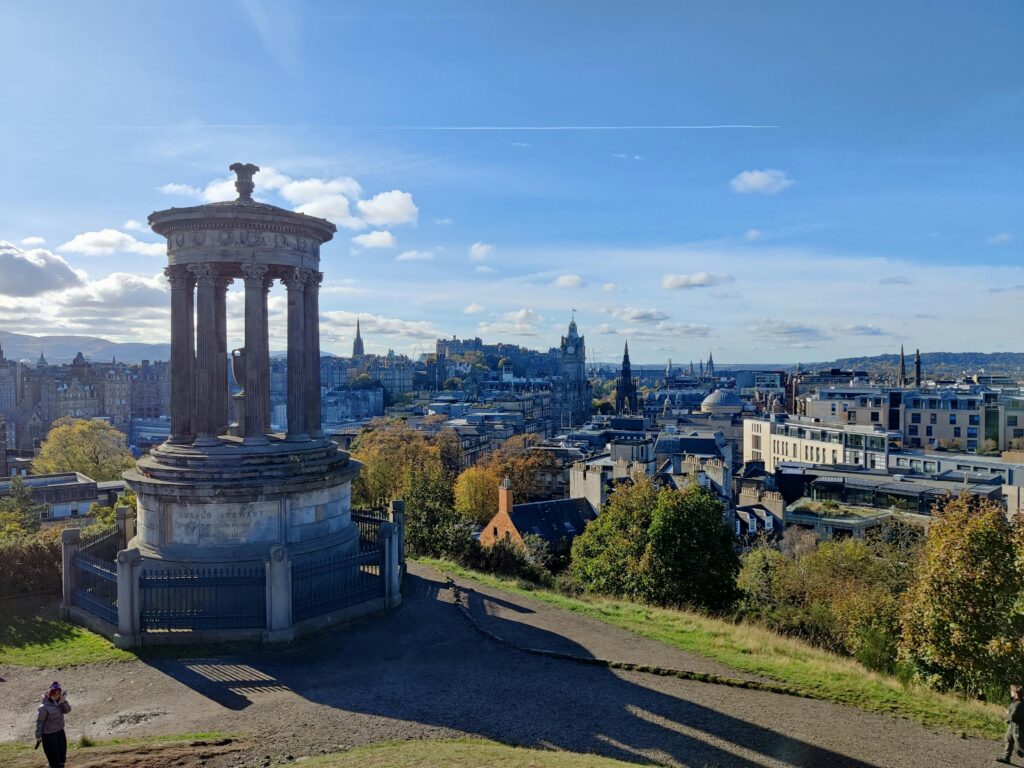 Spectacular cityscape of Edinburgh from Calton Hill, showcasing iconic landmarks under a clear blue sky.