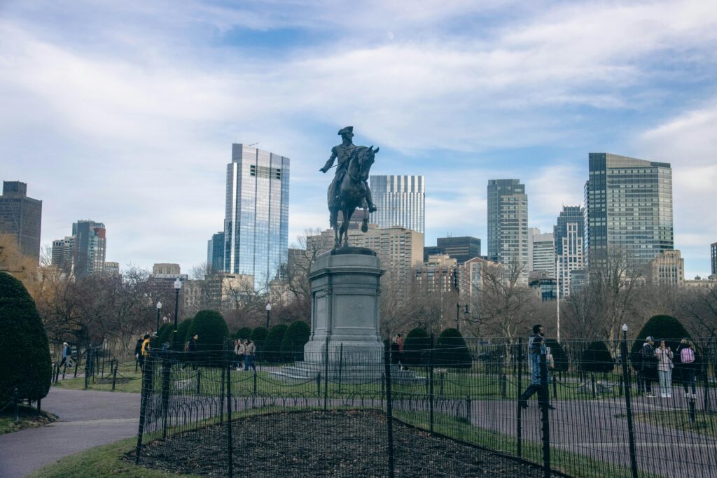 Equestrian statue of George Washington in Boston Public Garden against skyscraper backdrop.
