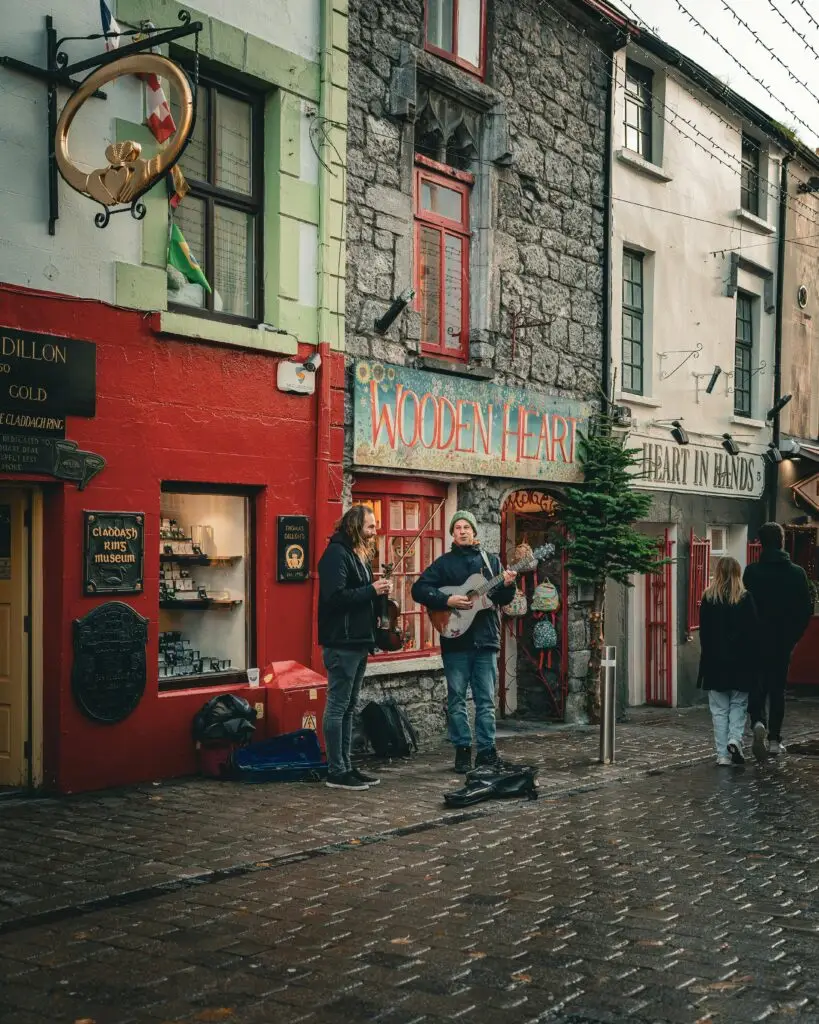 Street musicians performing on a cobblestone street in vibrant Galway, Ireland. Captivating urban scene.