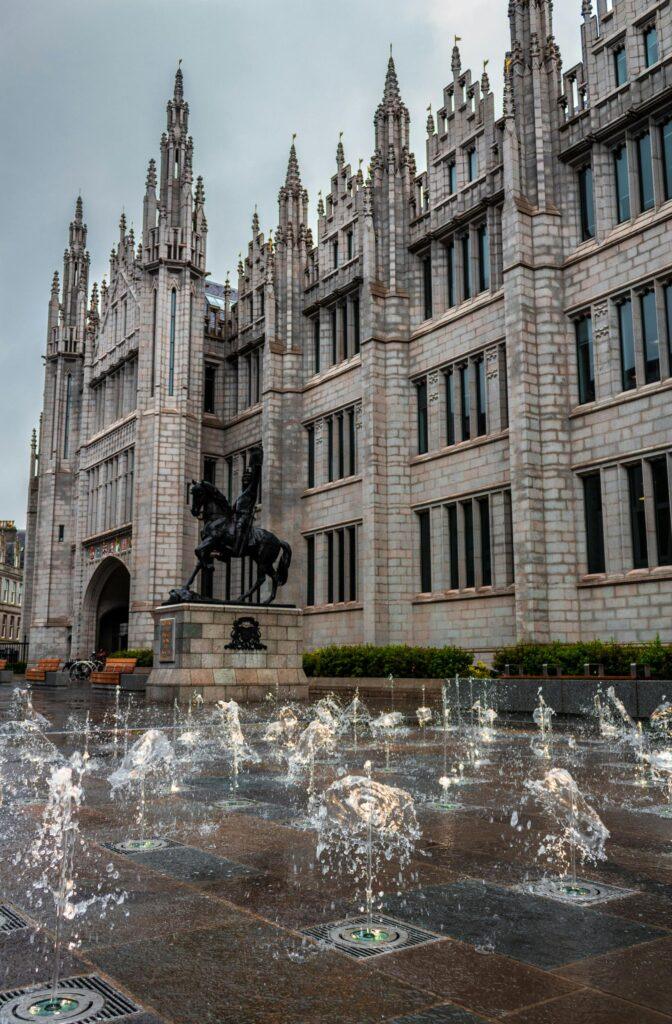 View of the iconic Marischal College with fountain in Aberdeen, Scotland showcasing Gothic architecture.