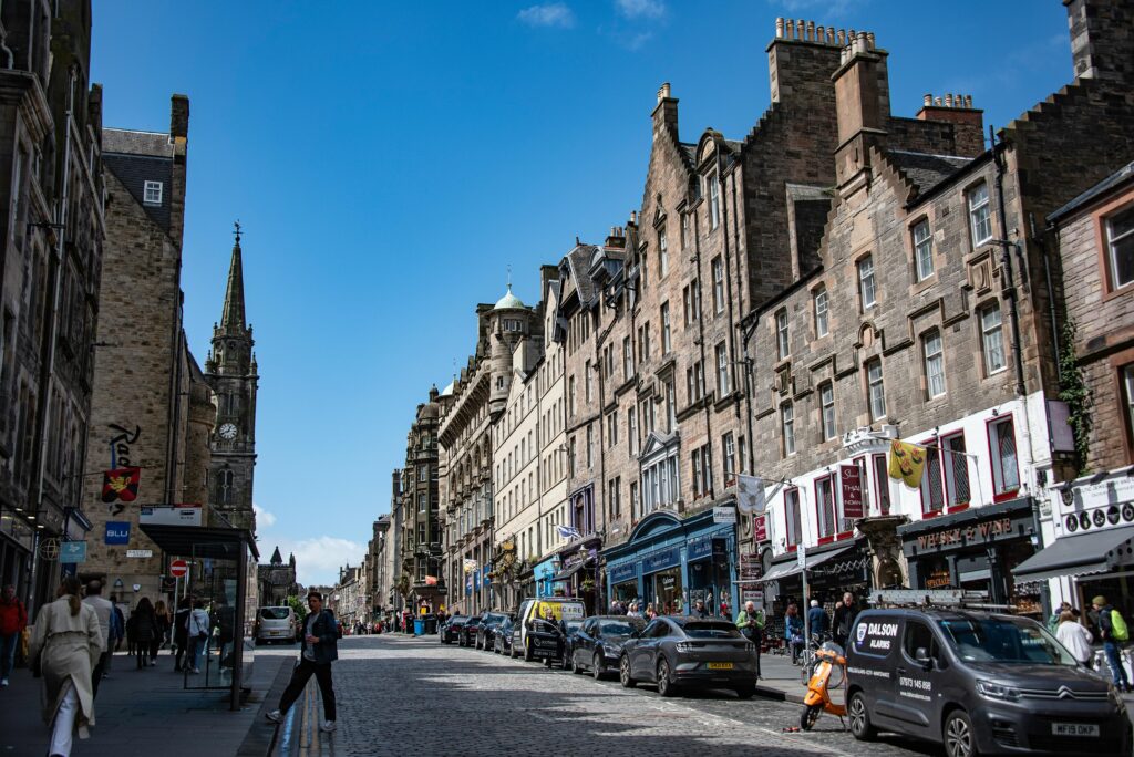 Explore the vibrant historic Royal Mile street in Edinburgh, Scotland with shops and architecture.