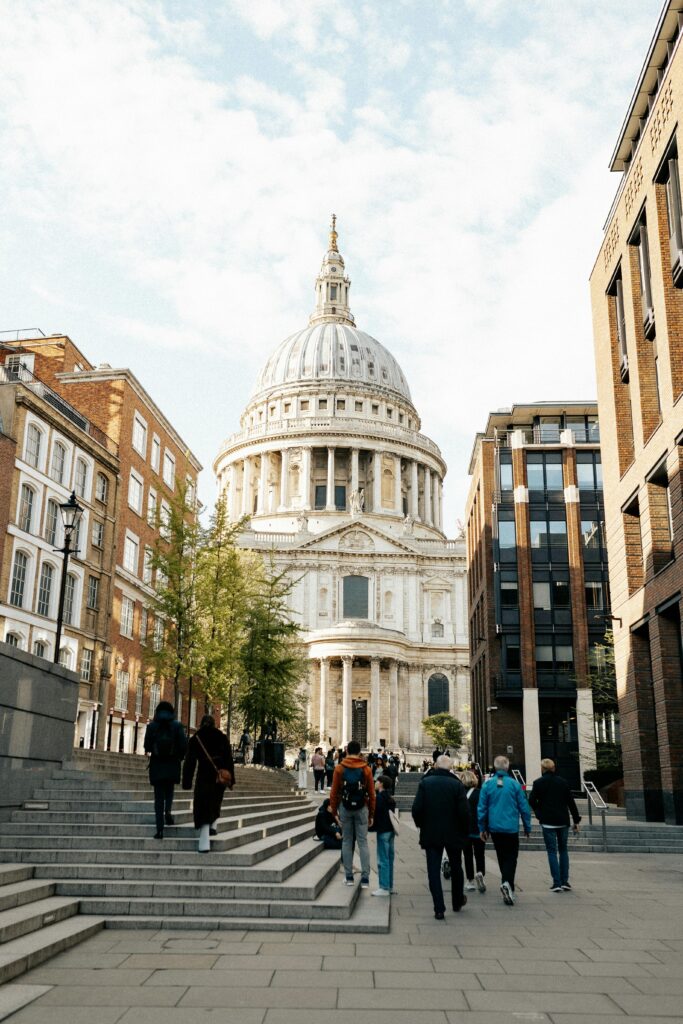 View of St Paul's Cathedral with people walking in London under clear skies.
